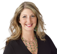 alicia Professional headshot of a smiling woman with long wavy blonde hair wearing a black top and beaded statement necklace