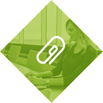 diamond-email Green diamond-shaped icon with white paperclip symbol overlaid on woman working at desk, representing document attachment services